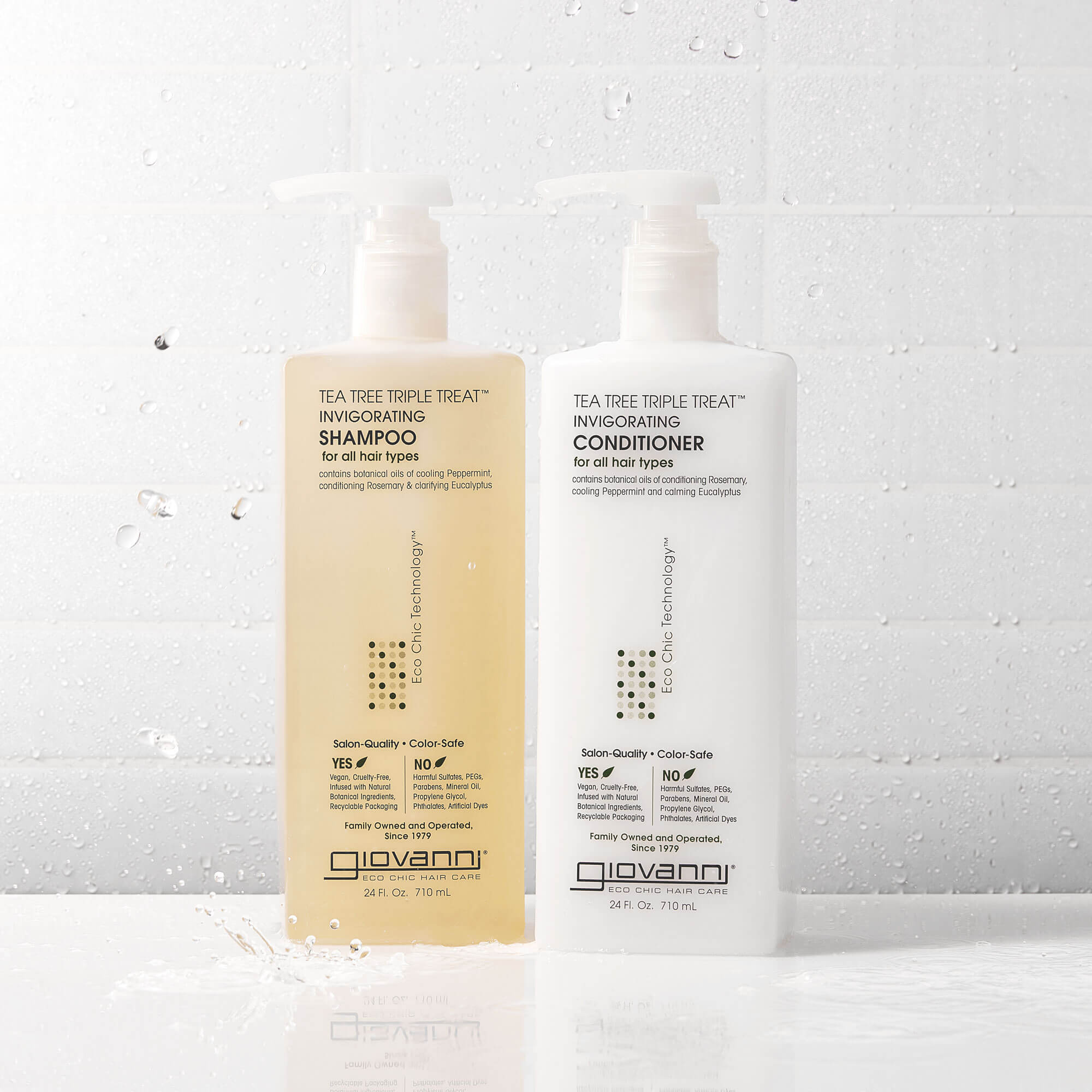 Two clear pump bottles labeled Giovanni Tea Tree Triple Treat Invigorating Shampoo and Conditioner are placed side by side on a white tiled surface with water droplets.