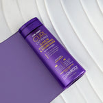 A purple bottle of Giovanni Cosmetics CURL HABIT™ Curl Defining Leave-In Conditioning & Styling Elixir for all curl types sits on a white and purple background, highlighting curl definition and moisturizing oils in gold and white text.