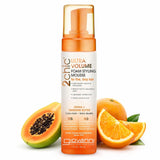A bottle of Giovanni Cosmetics 2chic® ULTRA-VOLUME FOAM STYLING MOUSSE stands among papaya and orange slices, showcasing its papaya and tangerine butter. This color-safe mousse is ideal for fine, limp hair.