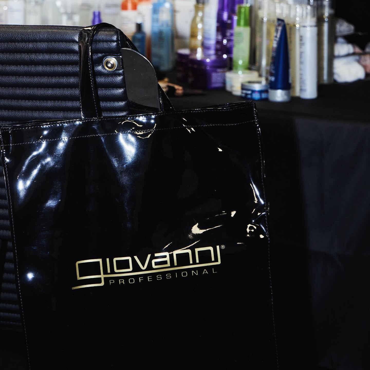 Black bag with 'Giovanni Professional' logo on a blurred background of Giovanni hair products.