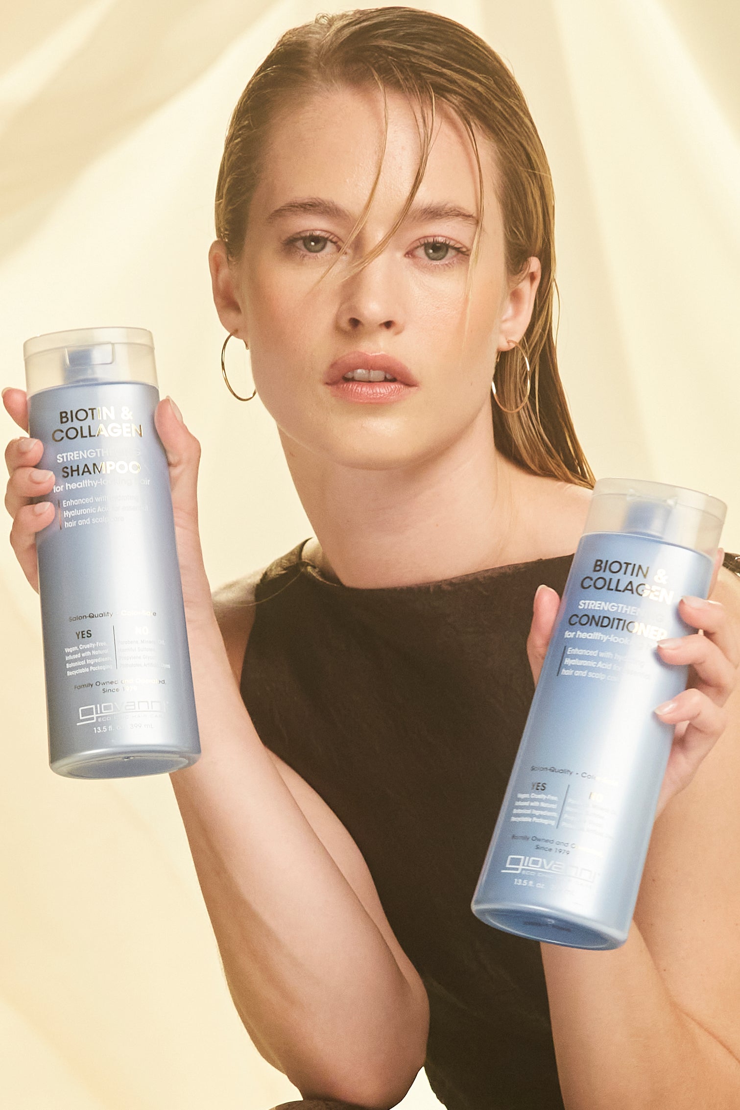 Woman holding bottles of Giovanni Biotin & Collagen Shampoo and Conditioner