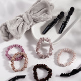 Five slim satin hair scrunchies in pink, beige, mauve, copper, and dark brown from Giovanni Cosmetics are arranged on a white surface with a white tray—perfect for elevating your daily hair care routine.