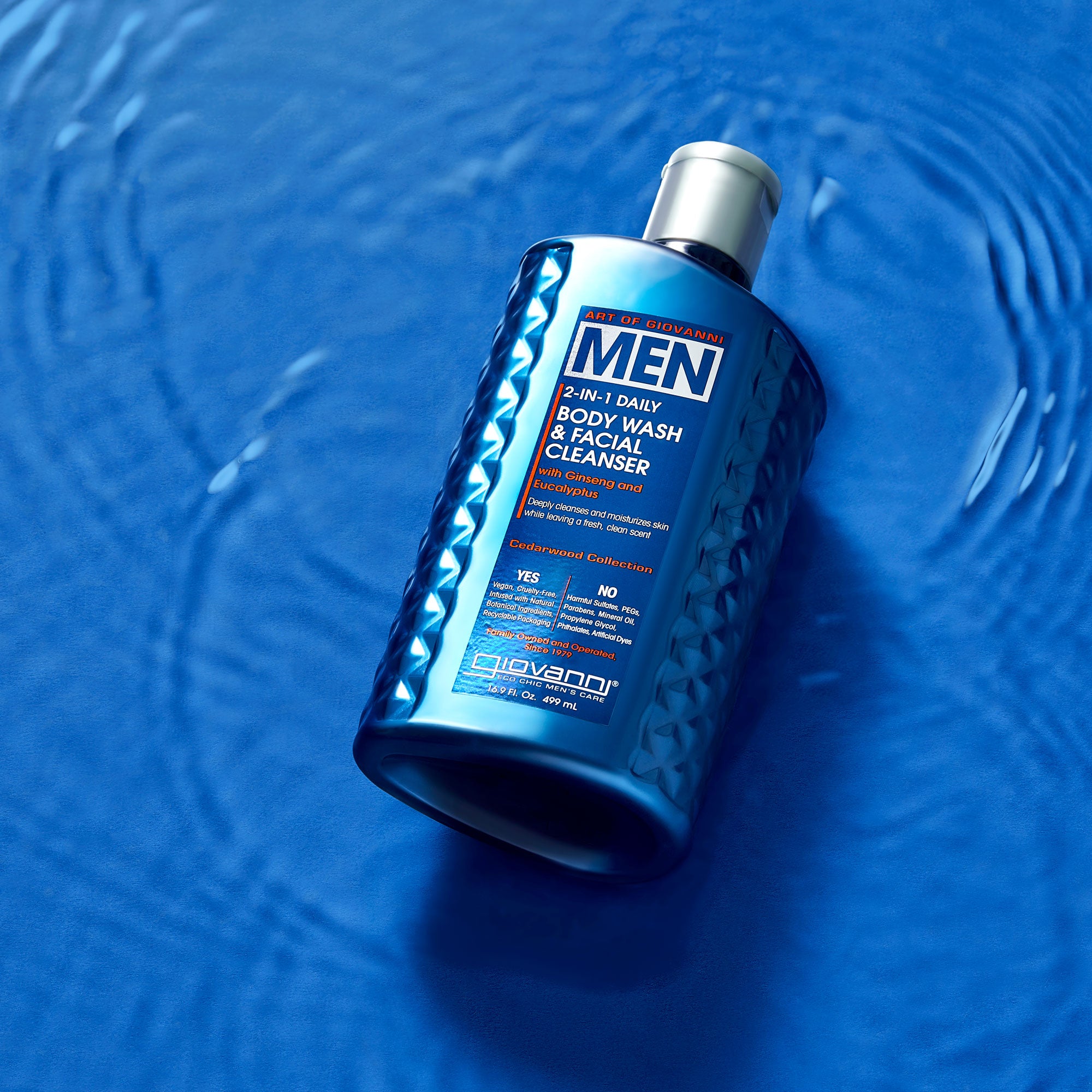 A blue bottle of Giovanni Cosmetics MEN 2-in-1 Daily Body Wash & Facial Cleanser with Ginseng & Eucalyptus rests on a rippling blue surface, viewed from above with product info visible on the label.