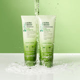 Two bottles of Giovanni Cosmetics 2chic® ULTRA-MOIST SHAMPOO (2 sizes) stand side by side on a wet surface as water splashes over them, set against a lush green gradient background.