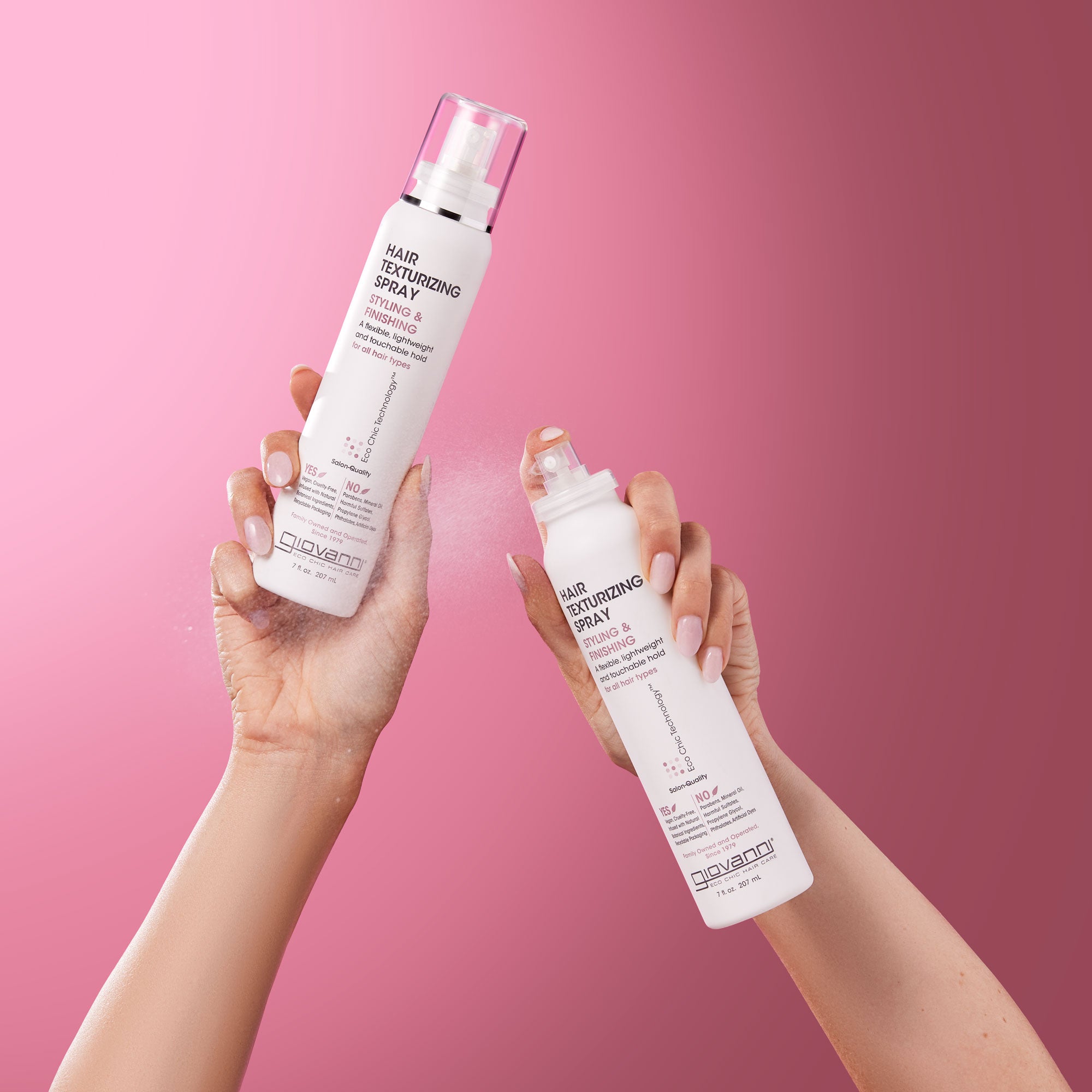Hands holding bottles of Giovanni Hair Texturizing Spray
