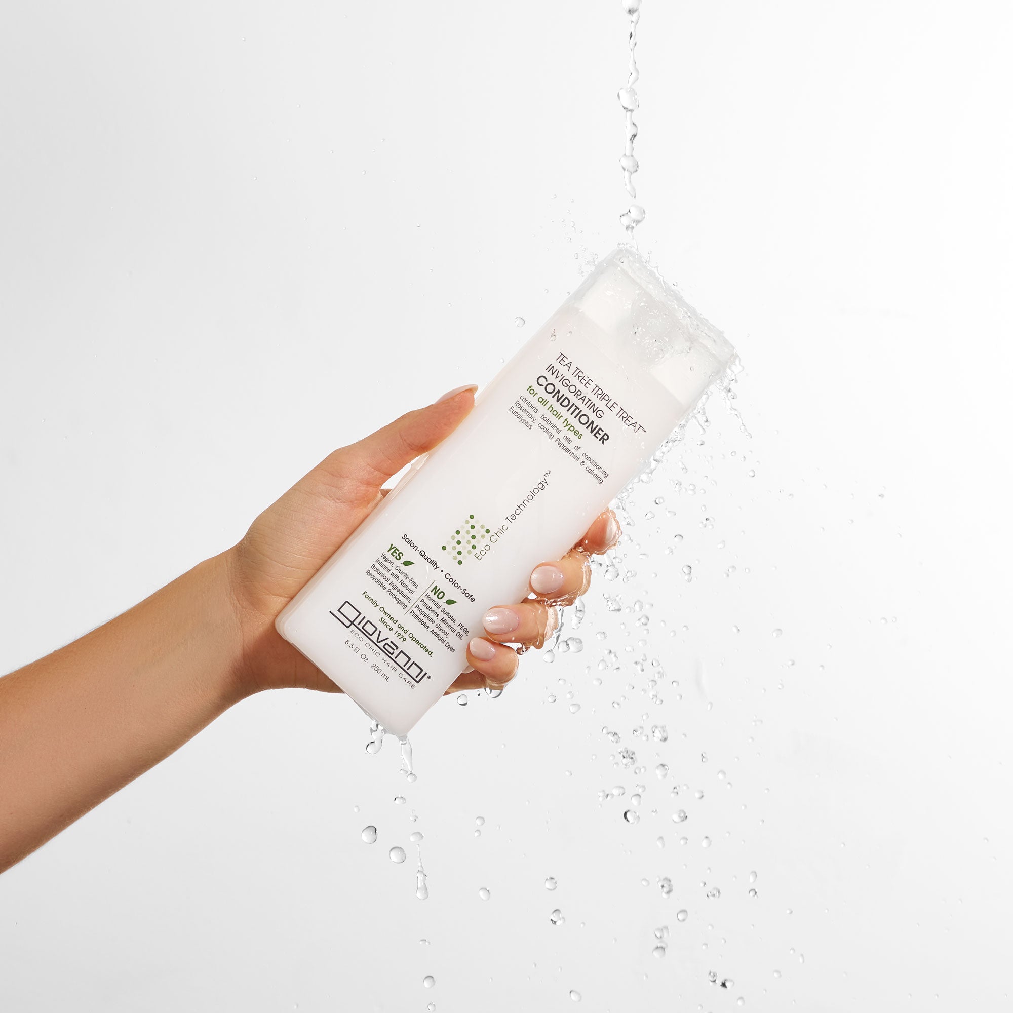 Hand holding Giovanni Tea Tree Triple Treat Invigorating Conditioner