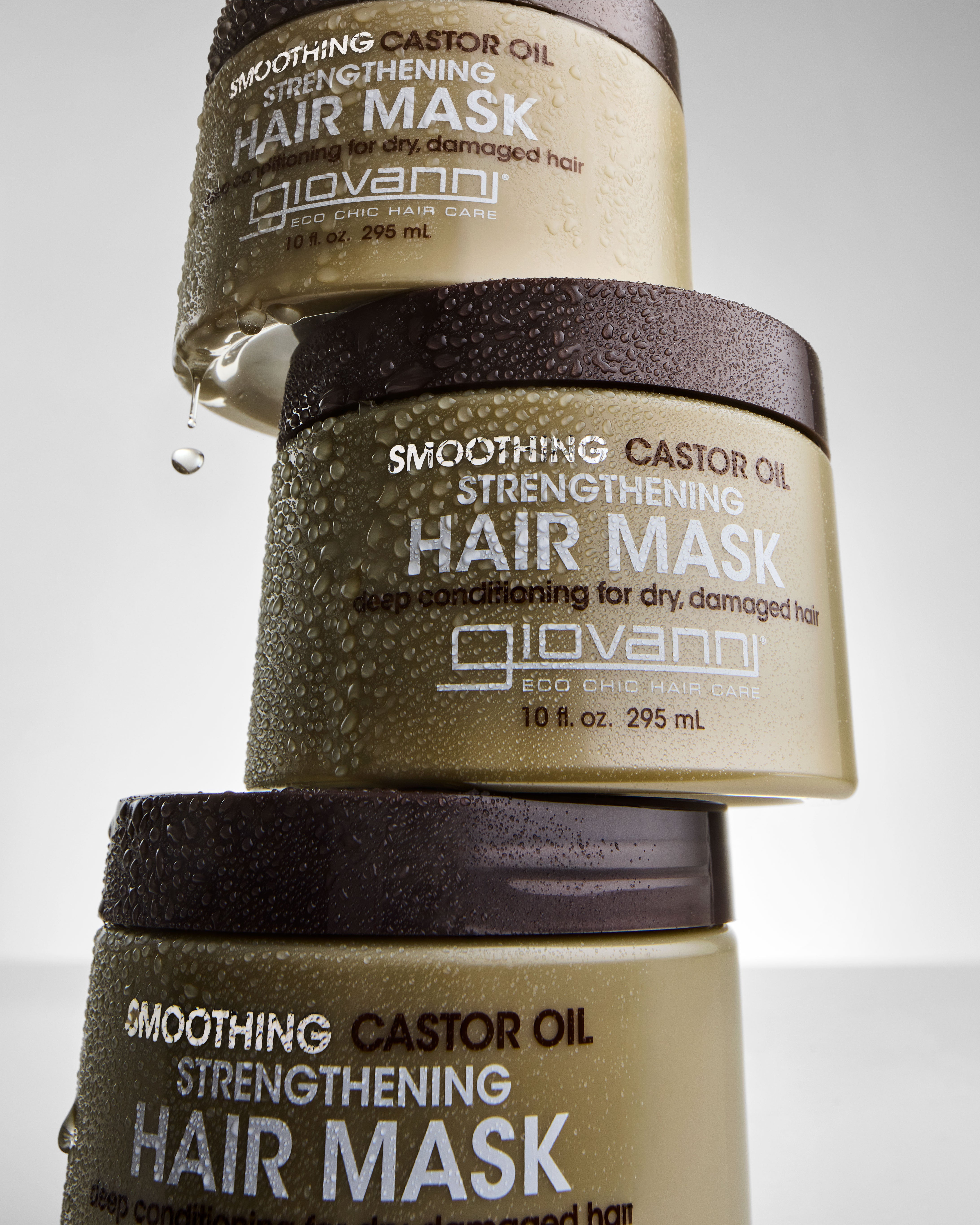 3 bottles of Smoothing Castor Oil Strengthening Hair Mask stacked on top of each other with water drops