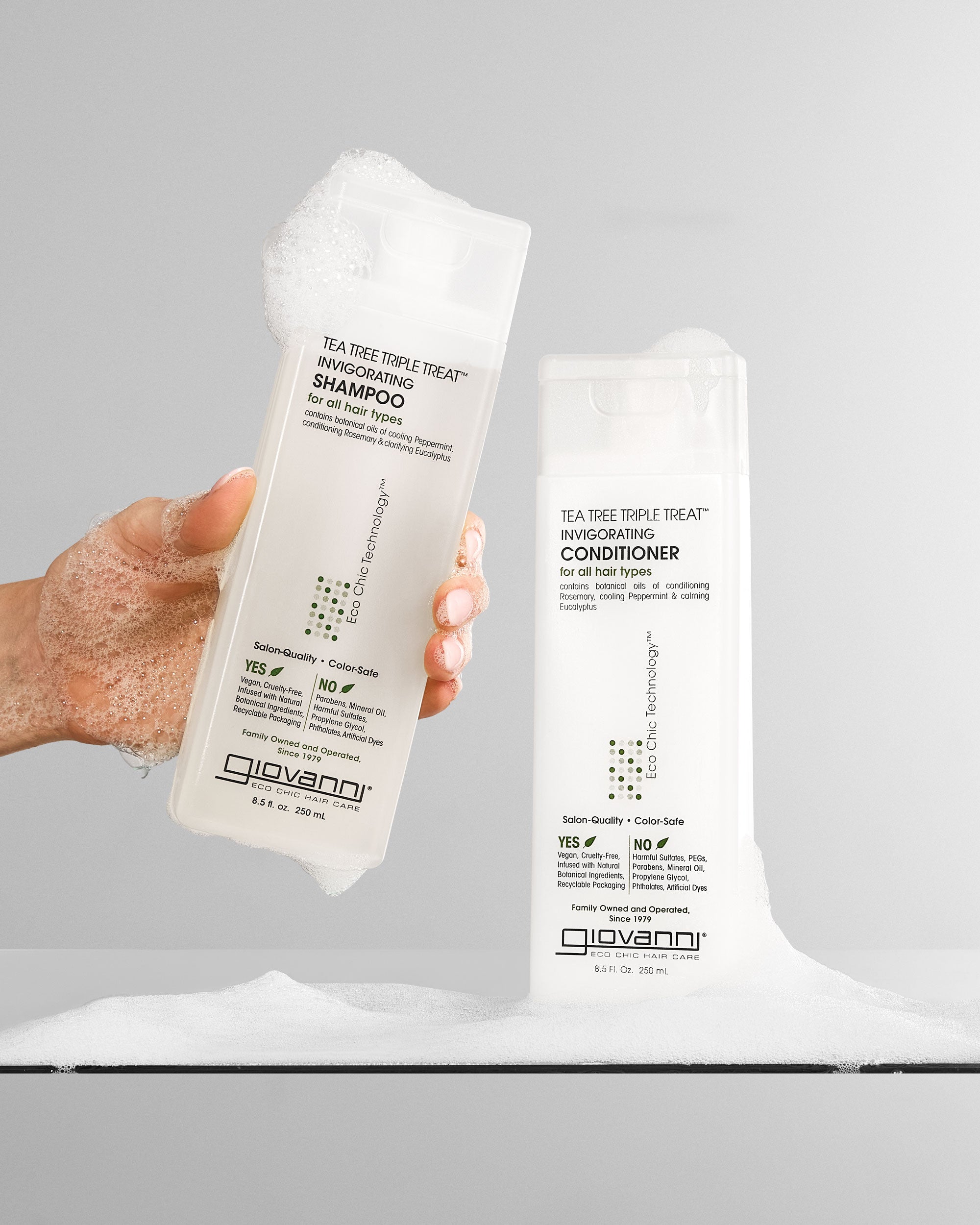 Hand holding Tea Trea Triple Treat Invigorating Shampoo and Conditioner