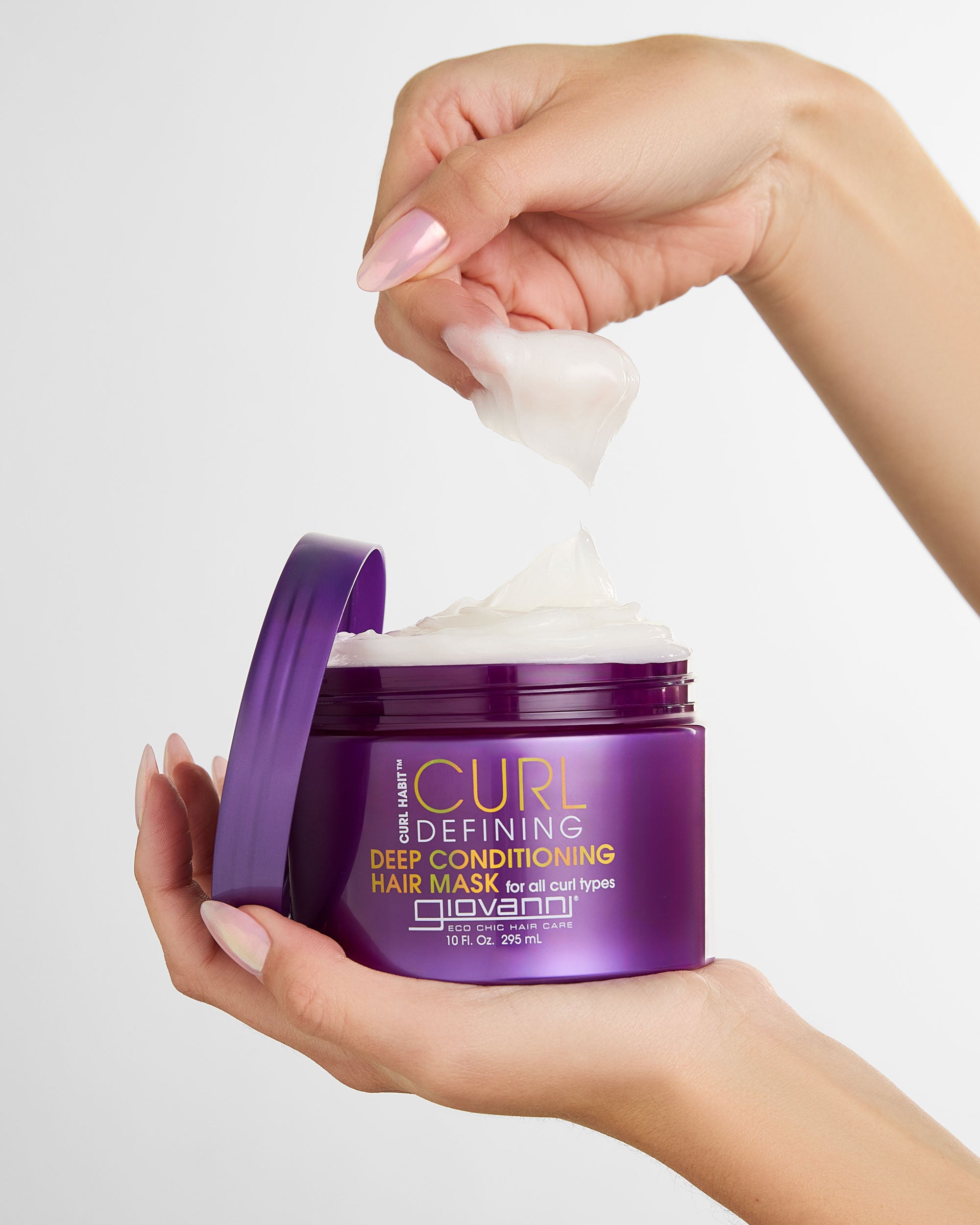 Jar of CURL Defining Deep Conditioning Hair Mask with a hand scooping out some of the product.