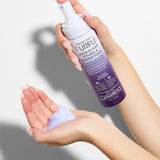 Giovanni Purple hair care product being held by a person with a neutral background