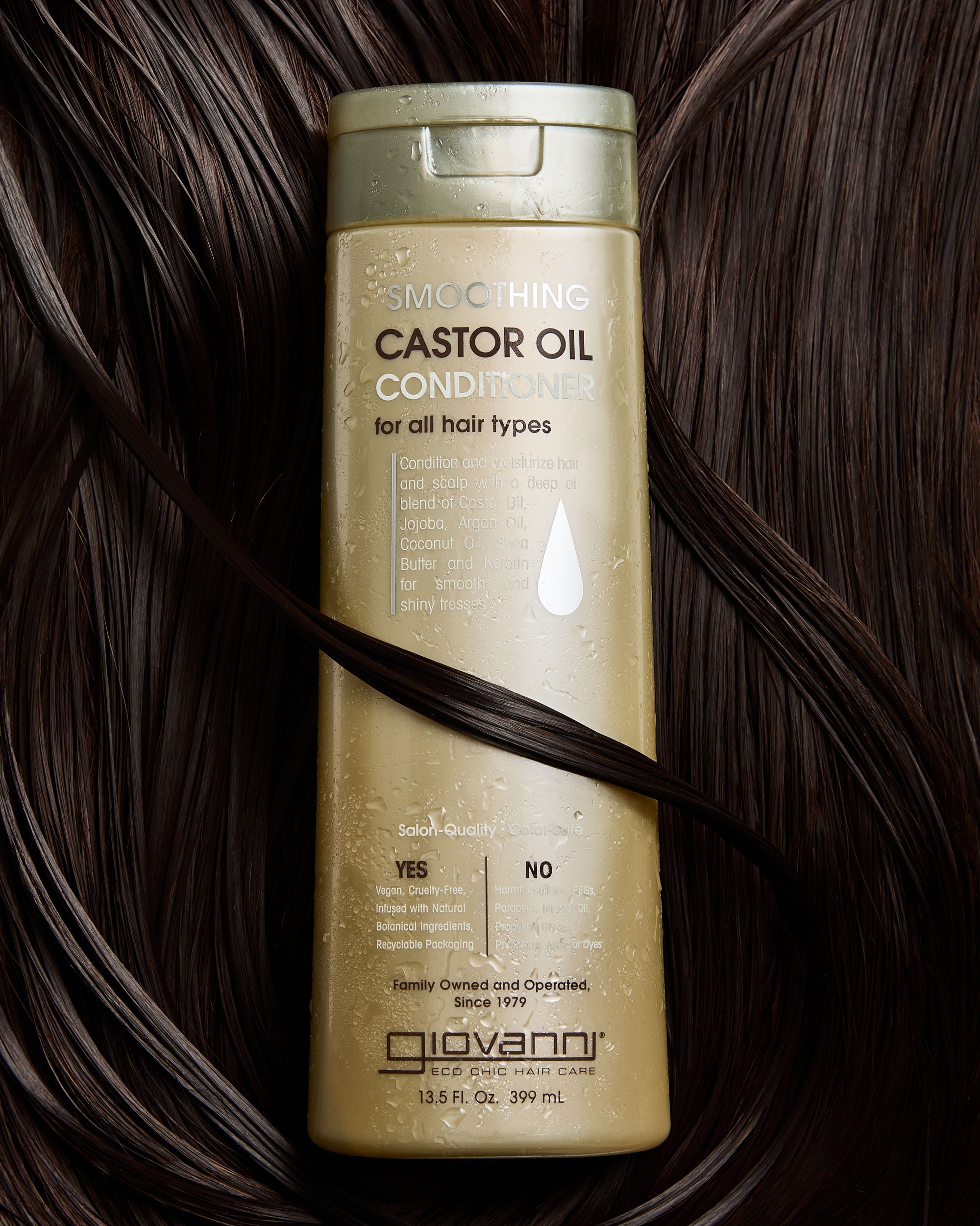 Giovanni Smoothing Castor Oil Conditioner bottle on a background of dark hair