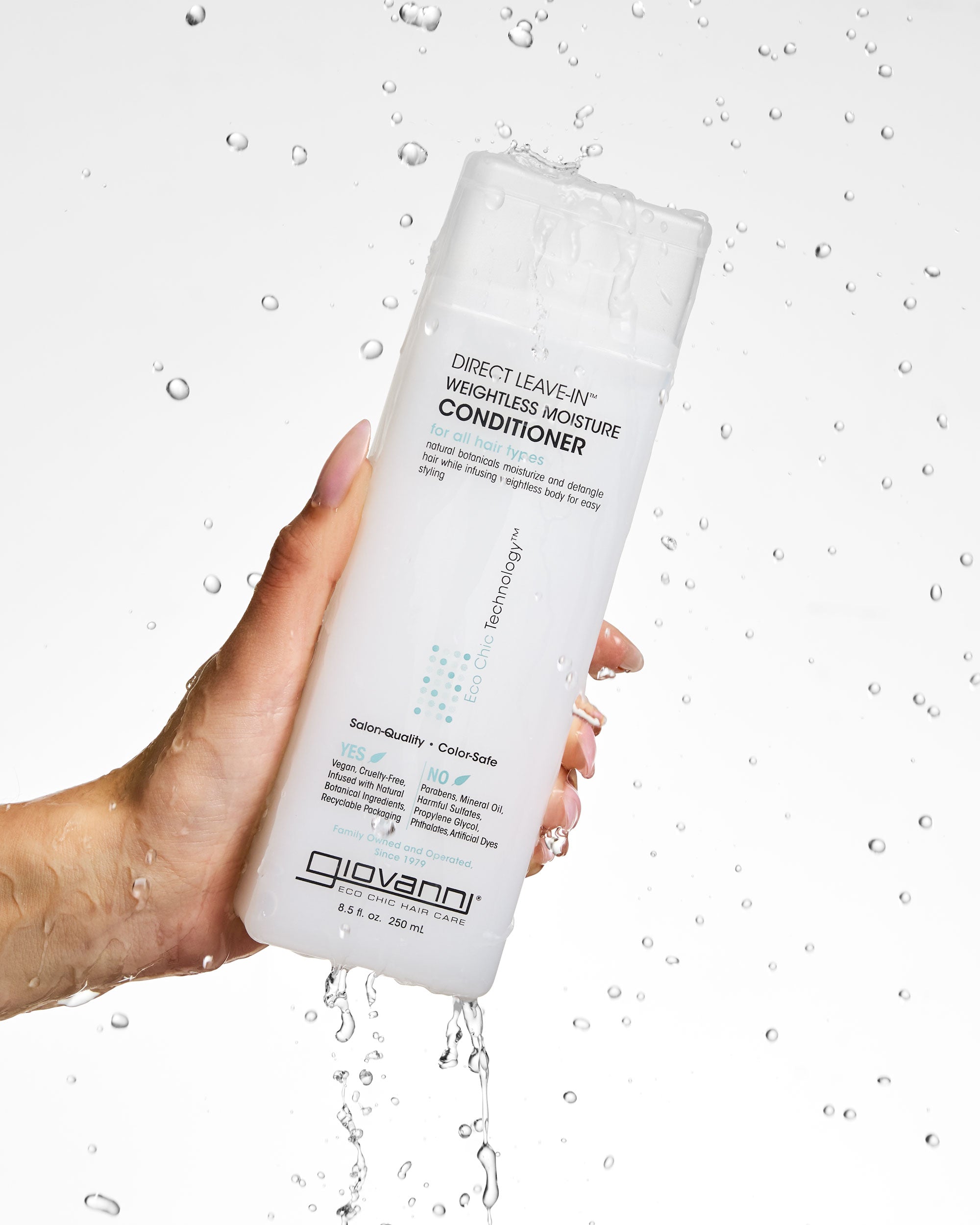 Hand holding a bottle of Giovanni Direct Leave-In Weightless Moisture Conditioner with water droplets in the background.