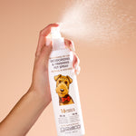Hand holding a bottle of Giovanni pet spray on a beige background