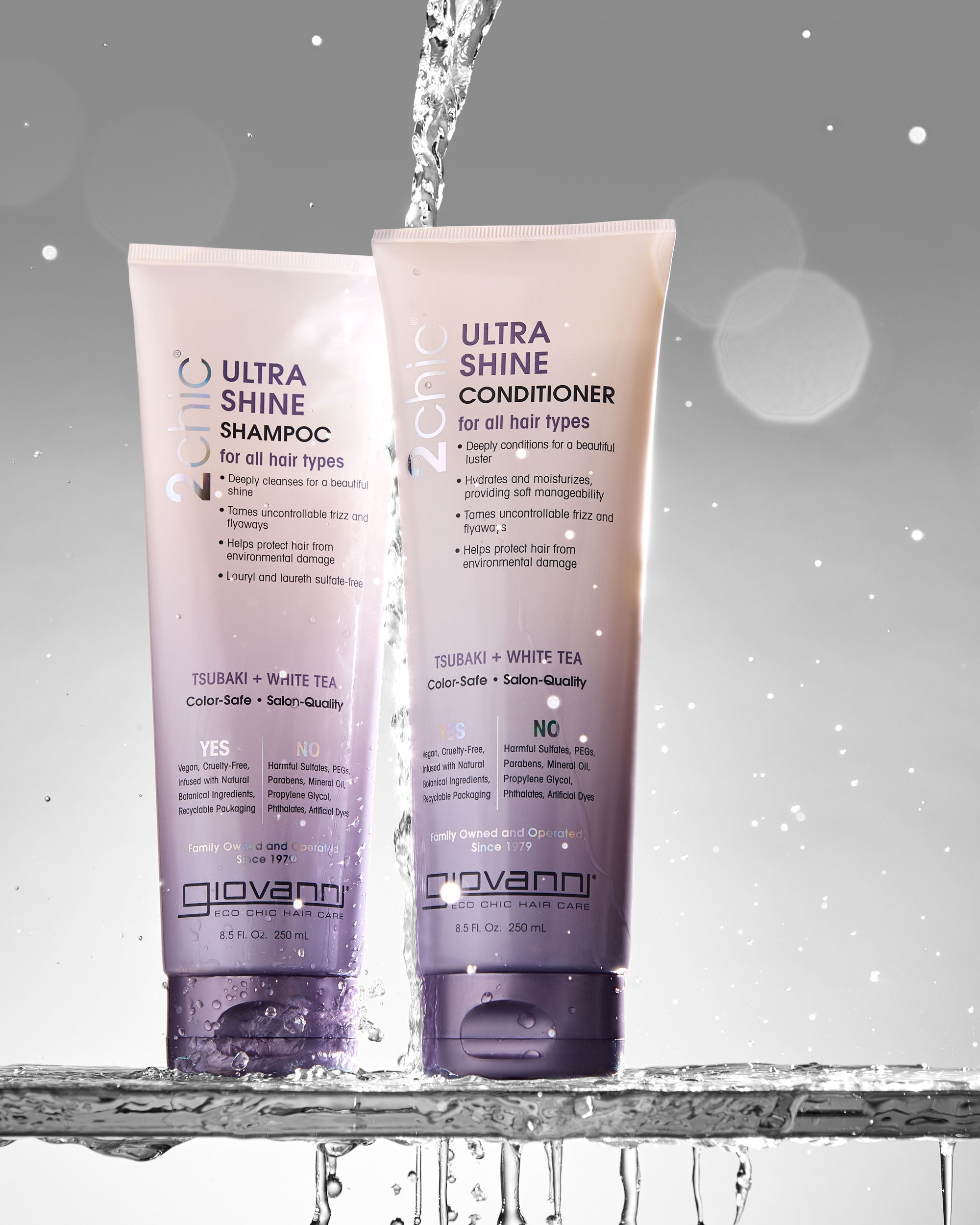 Two bottles of Giovanni Ultra Shine Shampoo and Conditioner on a gray background with water droplets.