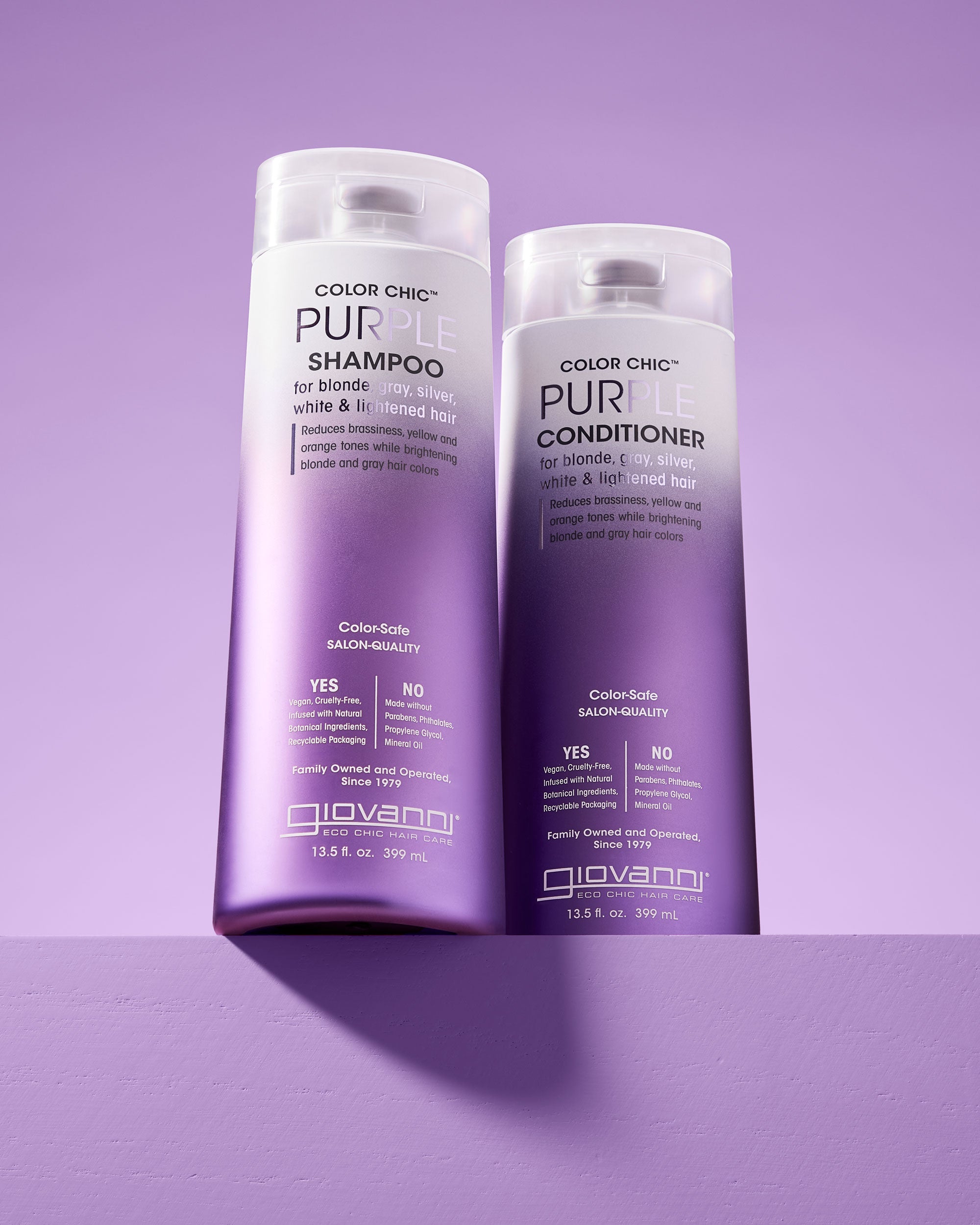 Two bottles of Giovanni Cosmetics COLOR CHIC™ PURPLE CONDITIONER for blonde, silver, gray, white, and lilac-toned hair stand side by side against a light purple background.