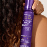 Giovanni Curl Habit Curl Activator Spray bottle held by a person with curly hair.
