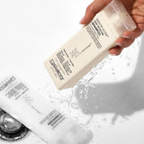 Hand holding a bottle of Giovanni Smooth as Silk Deep Moisture shampoo with on white background