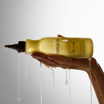 Hand holding a bottle of Giovanni Castor Oil with oil dripping