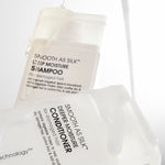 Two bottles of Giovanni Smooth as Silk shampoo and conditioner on a white background