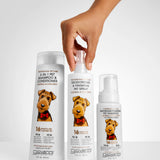 Three bottles of Giovanni pet care products with a hand holding one bottle on a light gray background