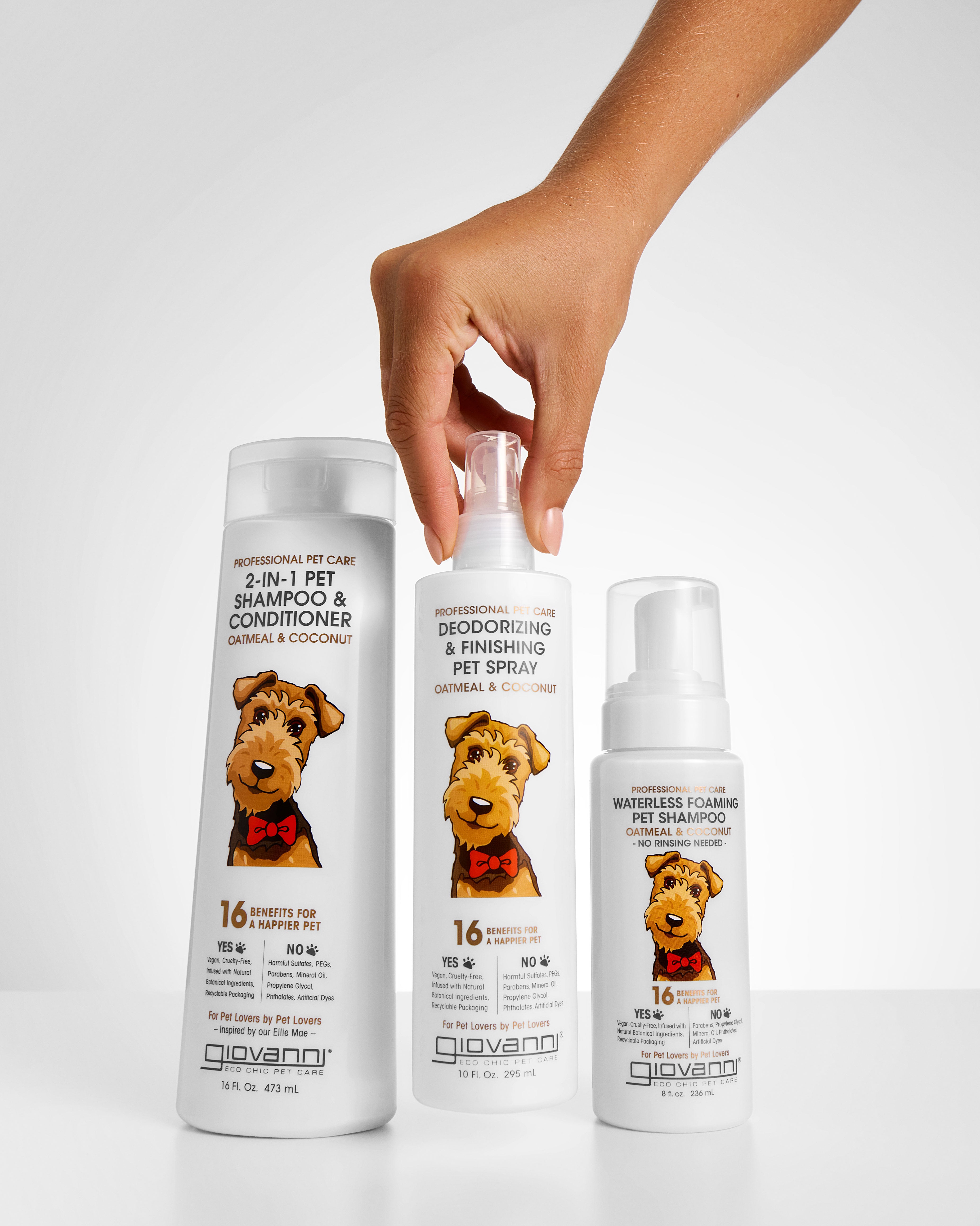 Three bottles of Giovanni pet care products with a hand holding one bottle on a light gray background