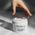 Hand reaching towards a jar of Giovanni Smooth as Silk Extreme Deep Conditioning Hair Mask product