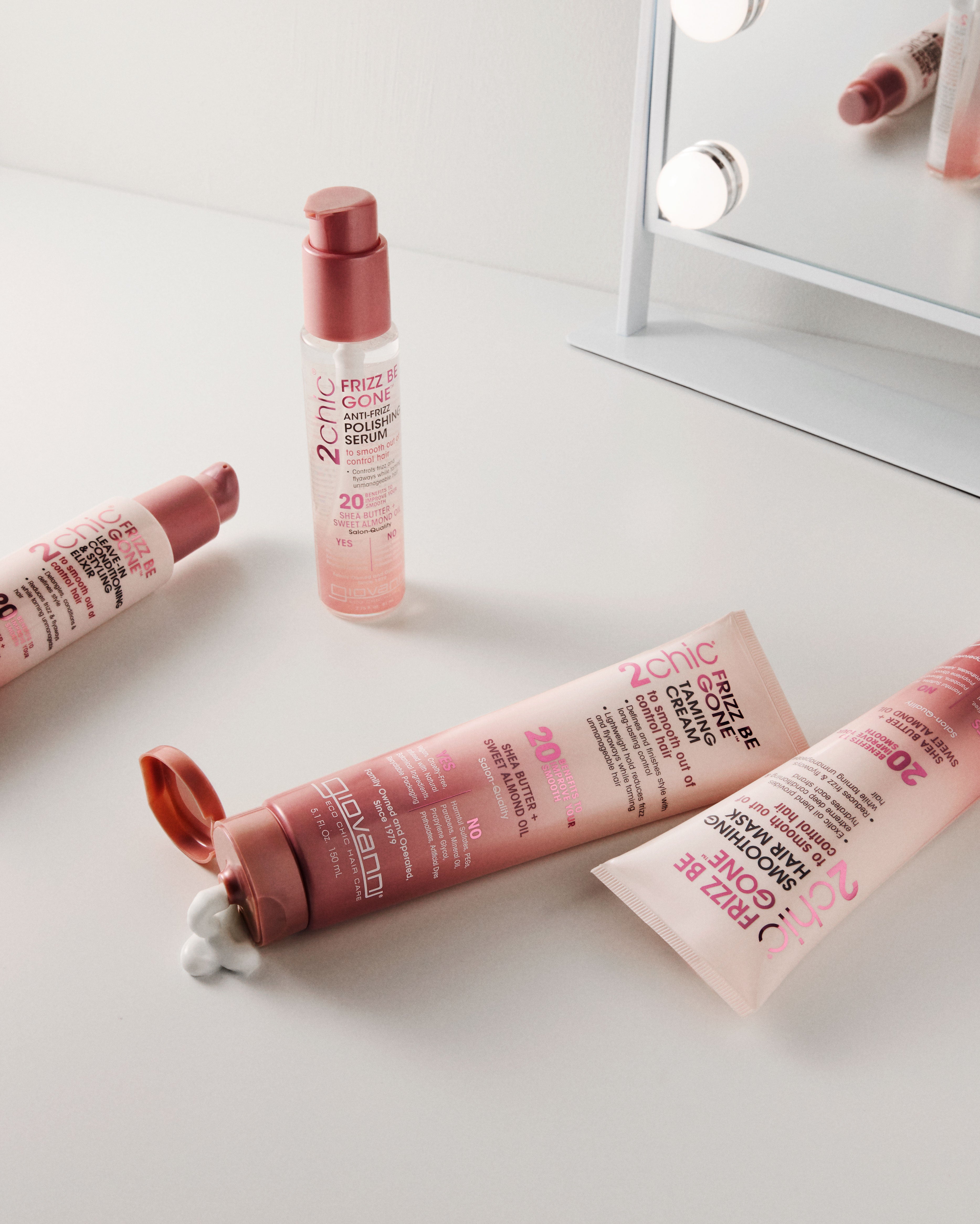 Giovanni 2chic Frizz Be Gone products on a white surface with a mirror in the background