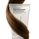 Giovanni hair thickener tube with brown hair wrapped around it on a white background