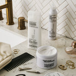 Giovanni products including bottles, a jar, and a comb on a bathroom counter with a tiled wall background.