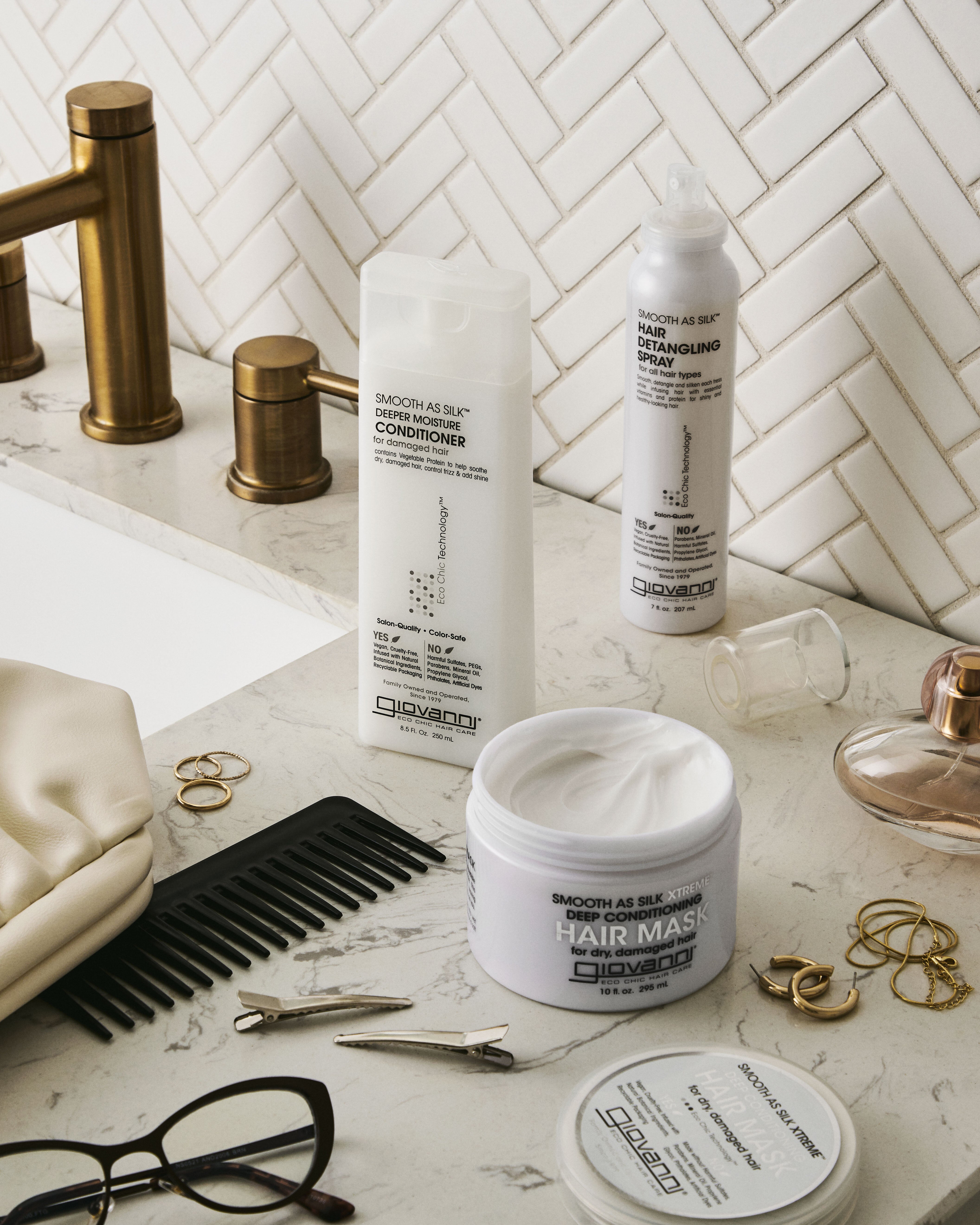 Giovanni products including bottles, a jar, and a comb on a bathroom counter with a tiled wall background.
