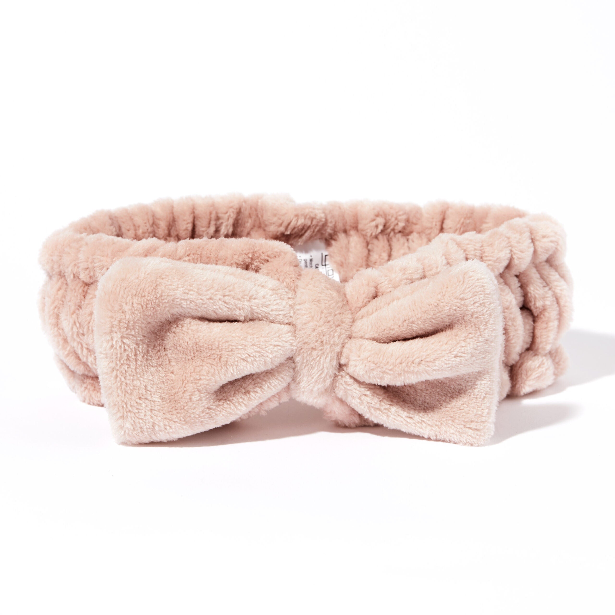 for all types of beauty routines  - The Giovanni Cosmetics PLUSH MULTI-PURPOSE SPA HEADBAND (blush) is a soft, light pink headband with a large bow and non-slip elastic—ideal for keeping hair in place during your beauty routine, shown on a white background.