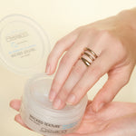 A hand with a gold ring dips into an open container of Giovanni Cosmetics WICKED TEXTURE™ THE DEFINITION OF POMADE against a light background.