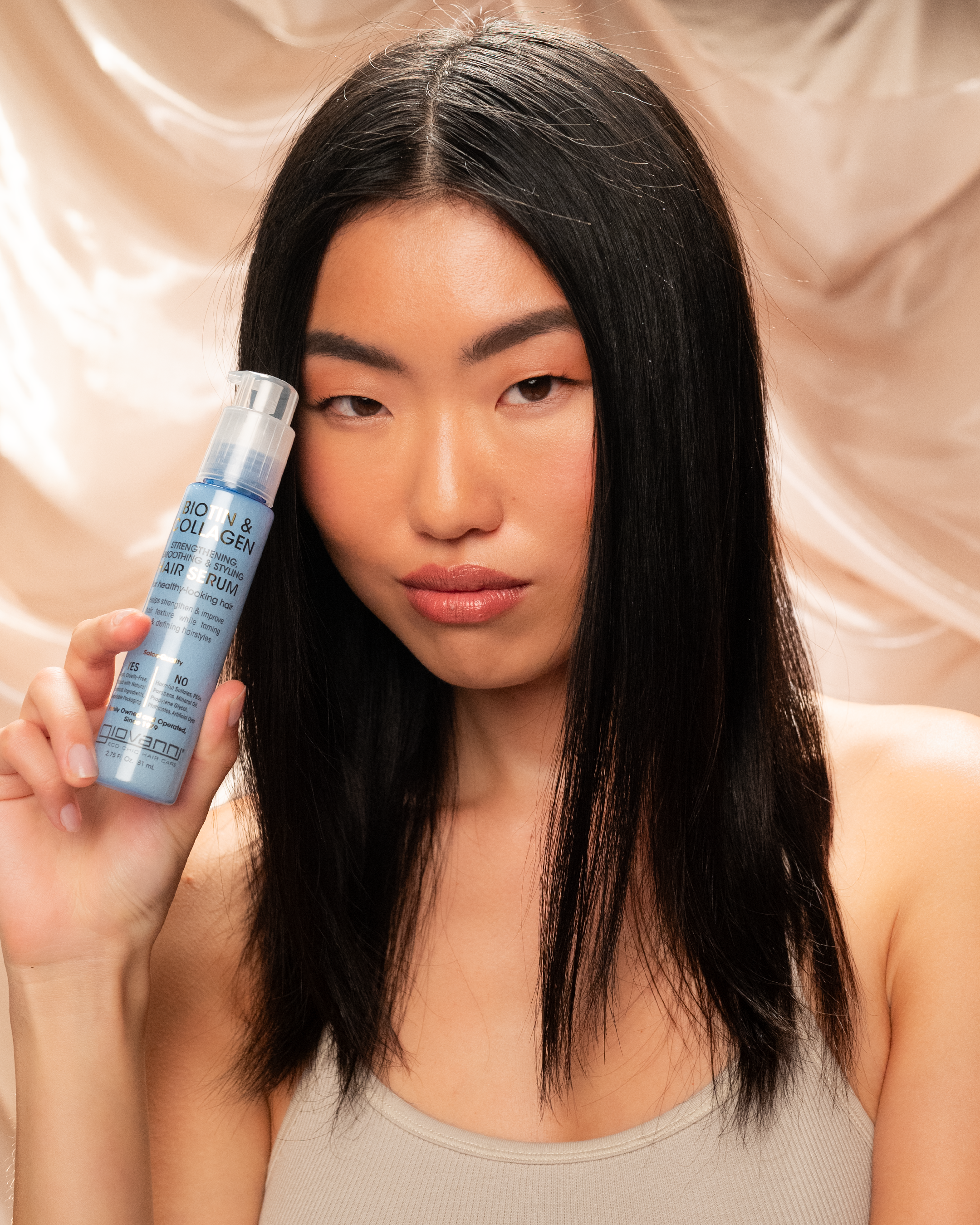 Woman holding a bottle of Giovanni Biotin & Collagen Hair Serum