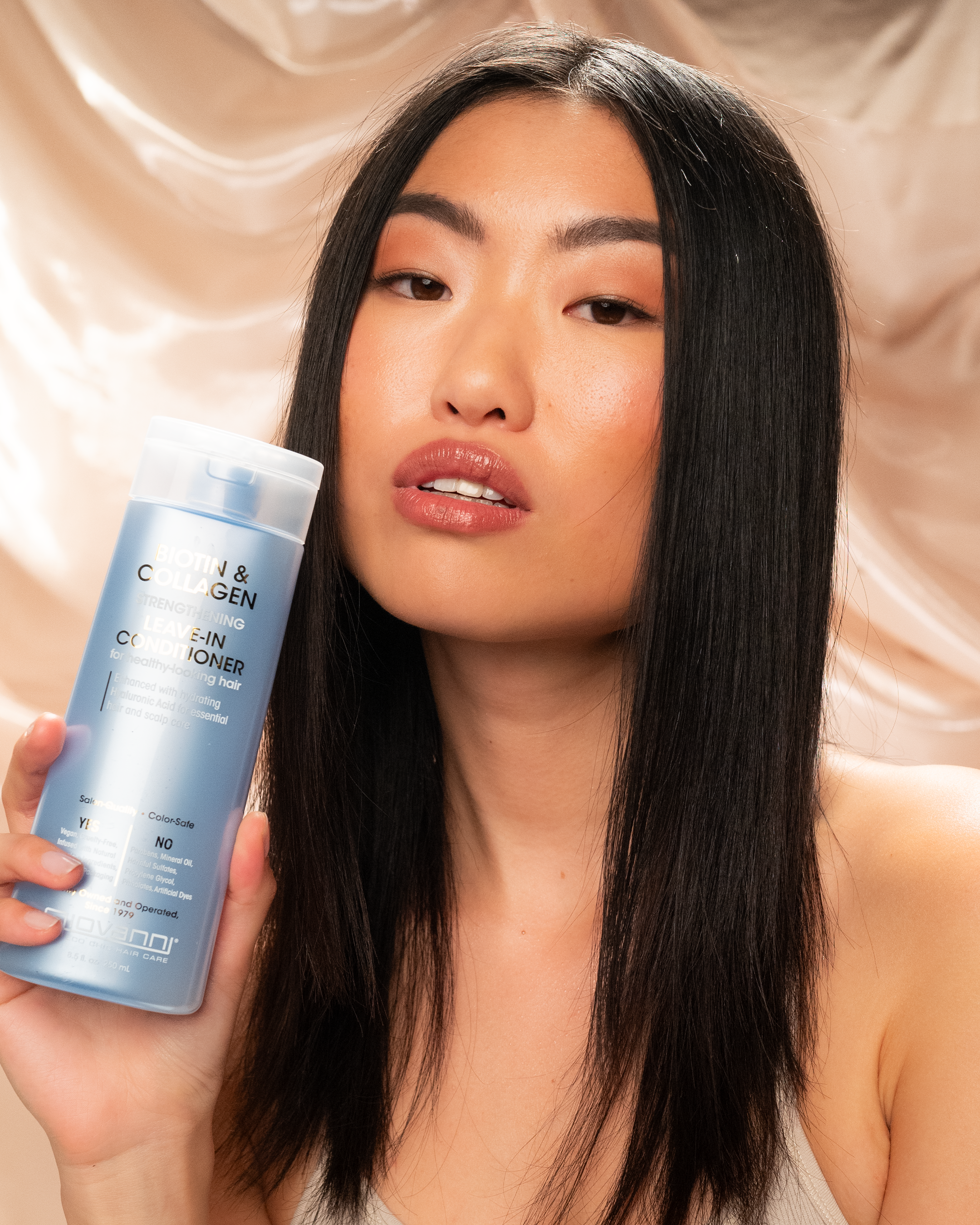Woman holding bottle of Giovanni Biotin & Collagen Strengthening Leave-in Conditioner