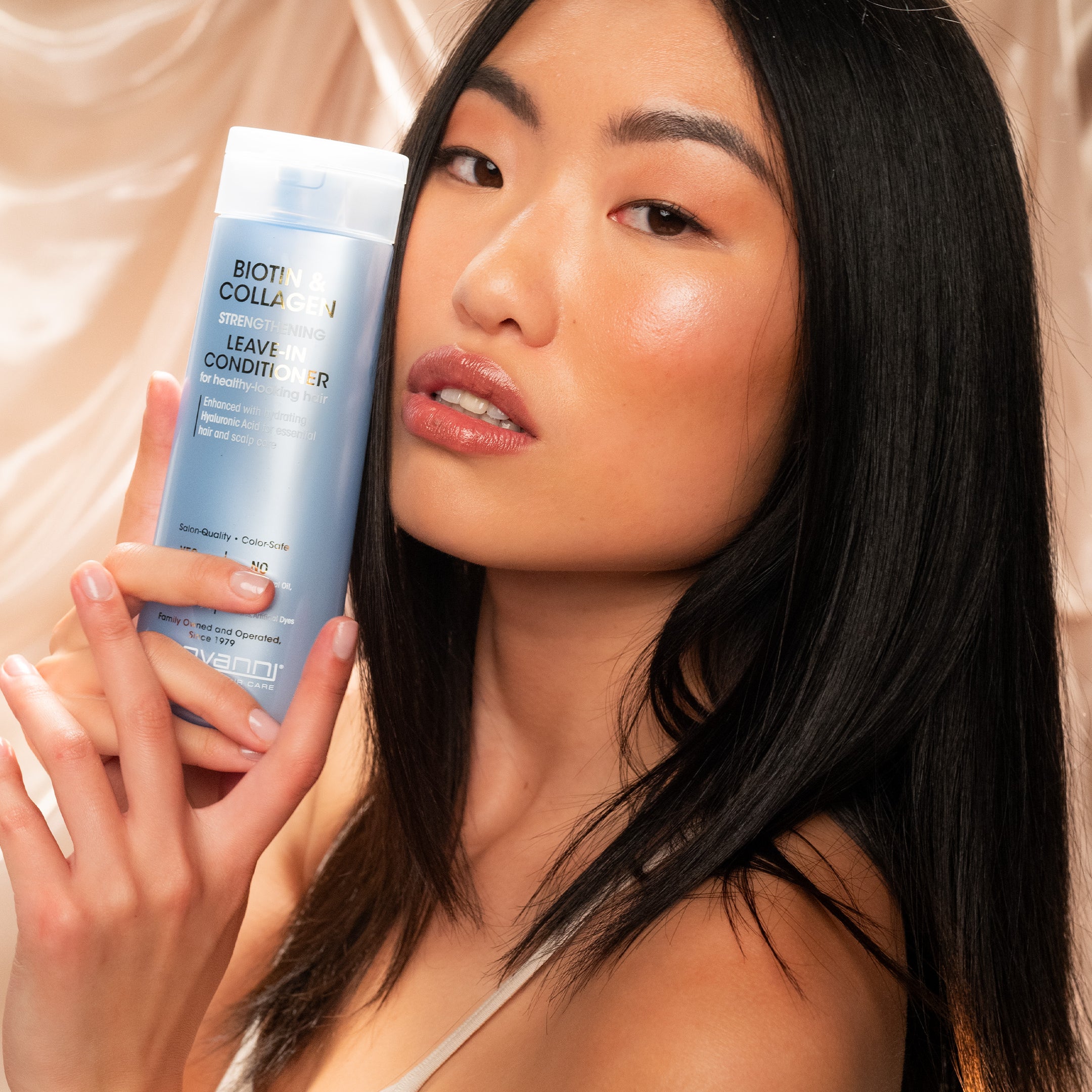 Woman holding bottle of Biotin & Collagen Leave-in Conditioner