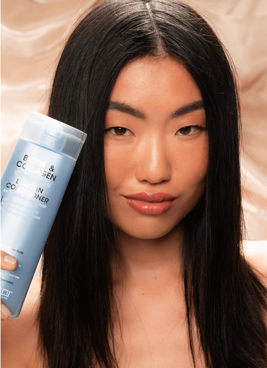 Woman holding bottle of Biotin & Collagen Leave-in Conditioner