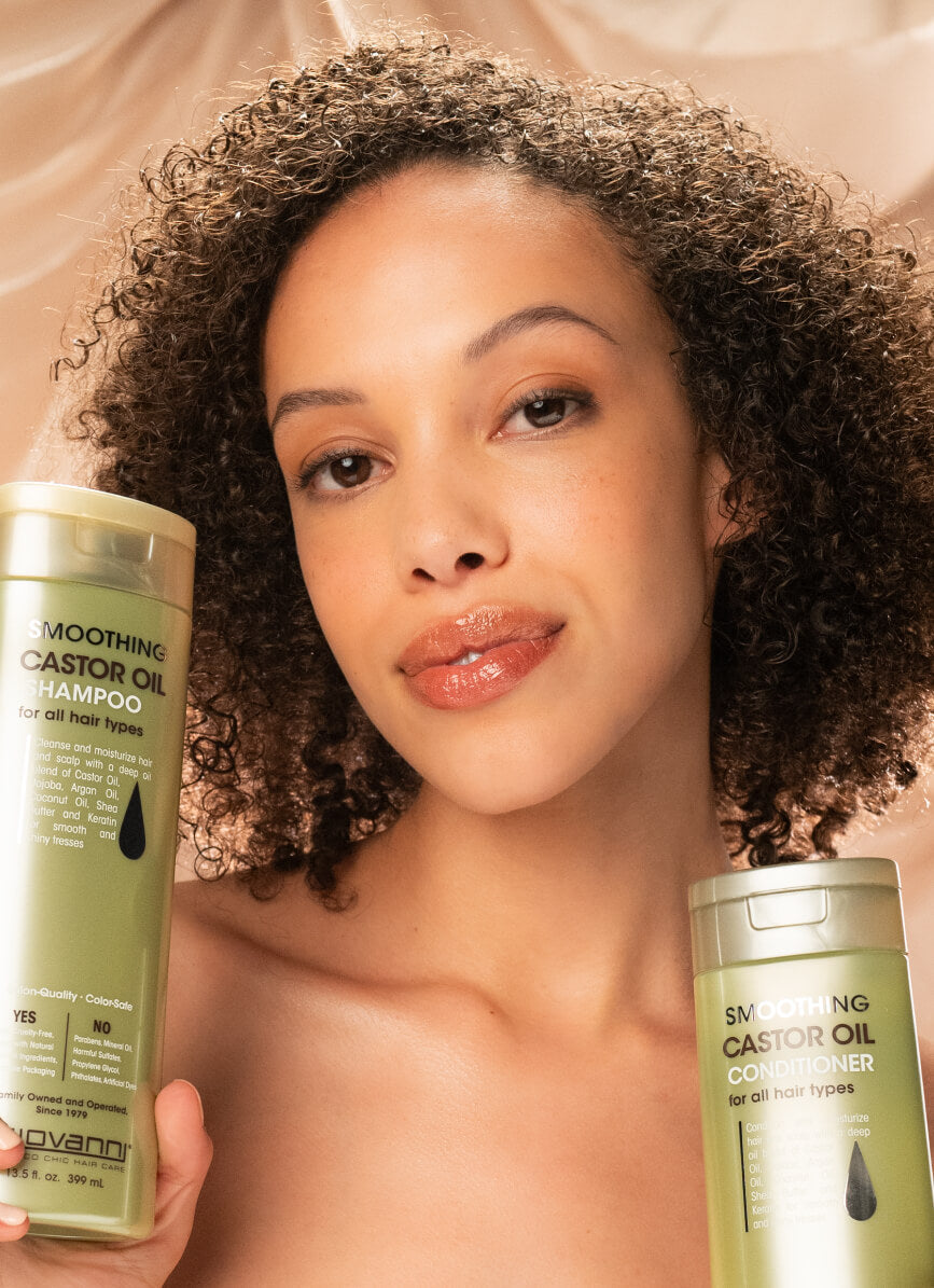 Woman holding bottles of Giovanni Smoothing Castor Oil Shampoo and Conditioner