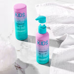 Two bottles of Giovanni Cosmetics' ECO CHIC® KIDS STYLING TAMING & CURL CREAM rest on white marble beside towels and a bath sponge, making it easy to care for your child's hair and define every curl.