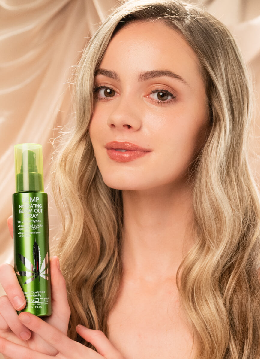 Woman holding bottle of Giovanni Hemp Hydrating Blow-Out Spray