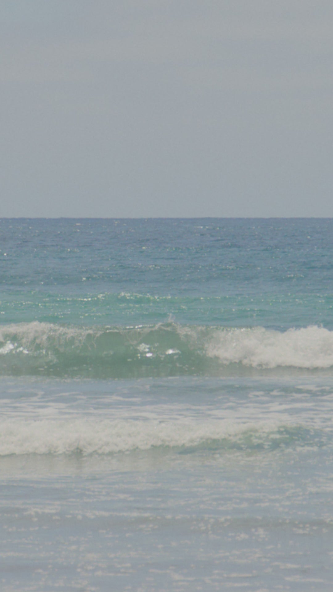 Video of woman on beautiful beach applying 2chic® ULTRA-SLEEK HAIR & BODY SUPER POTION OIL to her long brown hair.