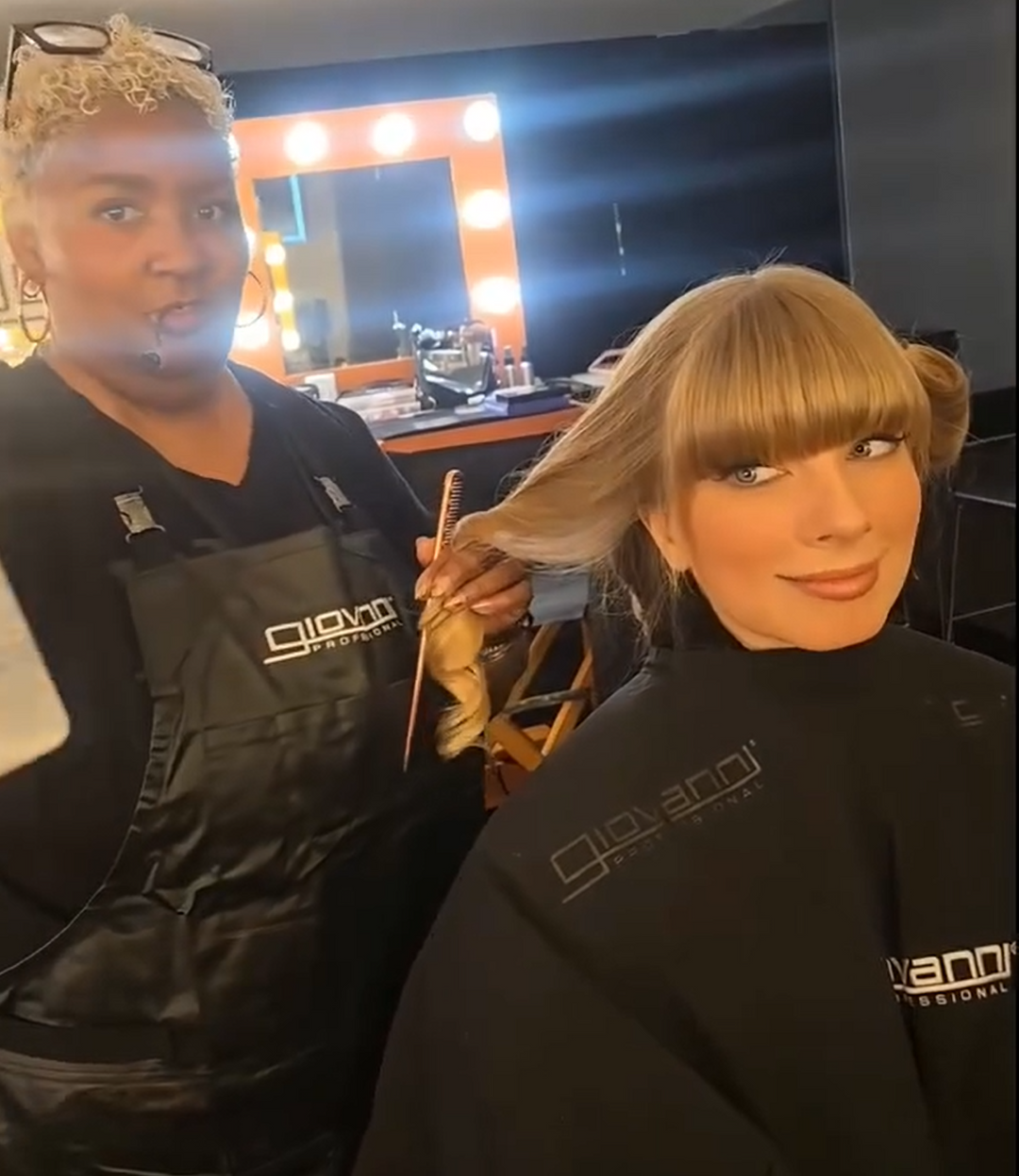 Hair stylists using Giovanni Hair Spritz on backstage model wearing a Giovanni Cape. They are backstage at the Grammy awards 