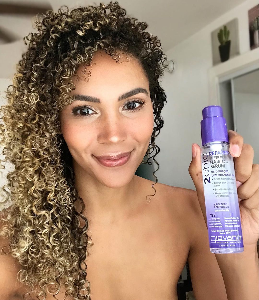 Woman holding bottle of Giovanni 2Chic Repair Super Potion Hair Oil Serum