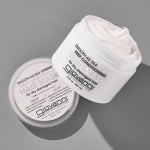 A white jar of Giovanni Cosmetics SMOOTH AS SILK XTREME™ DEEP CONDITIONING HAIR MASK, with its lid off and creamy conditioner visible inside, is displayed on a gray surface.