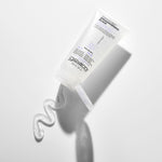 A clear squeeze tube of Giovanni Cosmetics STRAIGHT FAST™ Straightening Elixir lies on a white surface, cap open, with a wavy line of clear gel emerging from the nozzle.
